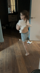 Young girl dances playfully indoors wearing casual clothes