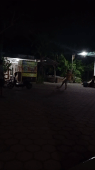 Nighttime street life around a lit commercial block in Ketegan