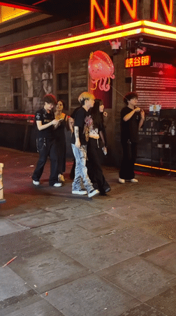 Young people walk city streets at night in Chongqing