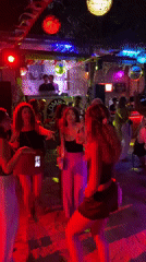 Tropical open-air night party with DJ, dancing, and colorful lights