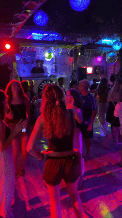 Tropical open-air night party with DJ, dancing, and colorful lights