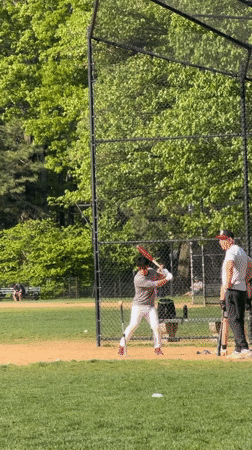 Baseball player practices hitting off tee in New York