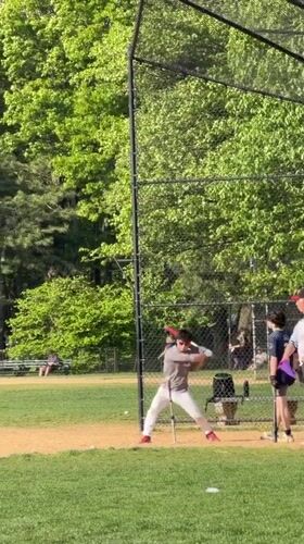 Baseball player practices hitting off tee in New York
