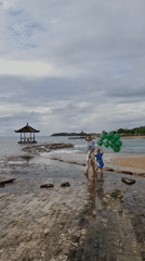 Woman, child play with balloons at Indonesian beach