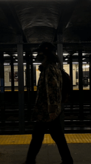 Woman with suitcase waits at NYC 23rd Street subway platform
