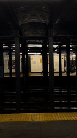 Woman with suitcase waits at NYC 23rd Street subway platform