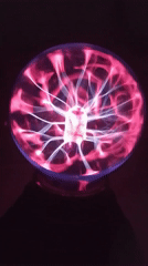 Person experiments with plasma ball in dark room