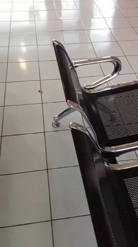 The video shows an empty waiting area with tiled floors and chairs. There are desks and windows, and the space appears to be well-lit. The camera pans across the room, showing different angles of the waiting area.