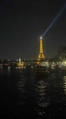Eiffel Tower glowing at night, Seine in the foreground
