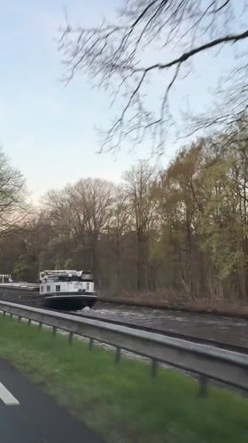 Barge travels canal in Erp amid spring foliage