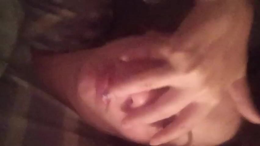 A close-up shot shows a hand with a wound on one of the fingers. Another hand is holding the injured finger, possibly examining or applying pressure to the wound. The background is blurred, but suggests a bed or soft surface. The lighting is dim and warm. The focus remains on the injured finger and the actions of the supporting hand.