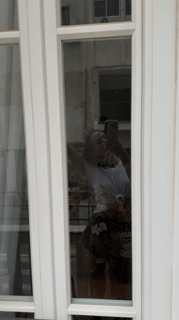 Woman takes flower bouquet selfie in Amman window reflection