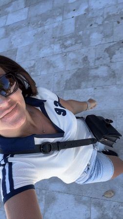 Woman films sunny walk near letter sculpture in Tivat