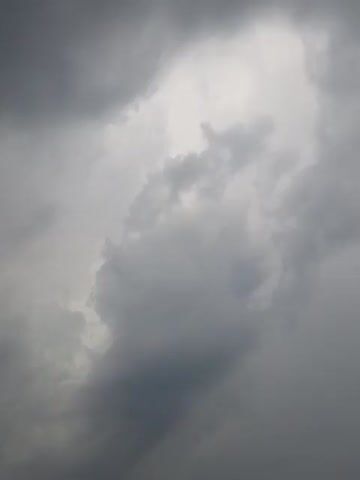 The video shows a close-up of dark, stormy clouds filling the entire frame. The lighting is dim, consistent with overcast weather. There are no people, objects, or discernible actions visible. The scene is purely environmental, focusing on the atmospheric conditions of heavy cloud cover.