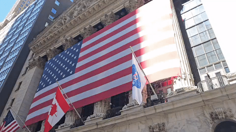 NYSE building displays American, Canadian flags with unidentified banner