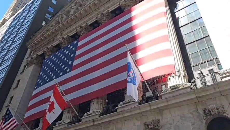 NYSE building displays American, Canadian flags with unidentified banner