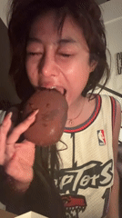 Woman in Raptors jersey eats chocolate donut Friday morning