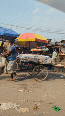 Man pushes tricycle cart through Dhaka marketplace