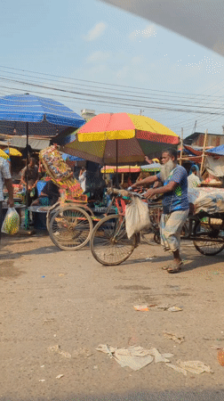 Man pushes tricycle cart through Dhaka marketplace