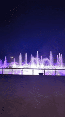 Lit fountains and moonlight over a Moscow park lake
