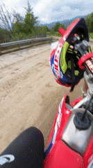 Red dirt bike with helmets spotted on rural road