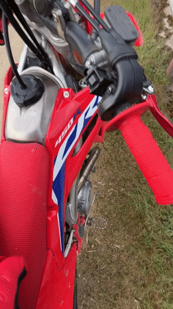 Red dirt bike with helmets spotted on rural road