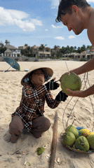 Coconut vendors serve tourists on Vietnamese beach in Phu Thuy Ward
