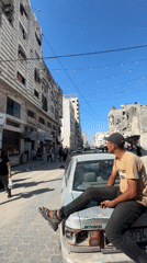 Young men gather on Gaza streets amid damaged buildings