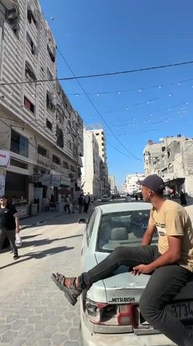 Young men gather on Gaza streets amid damaged buildings