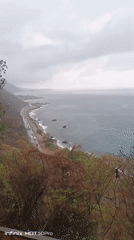 Person spotted on offshore rock formation along coastal road