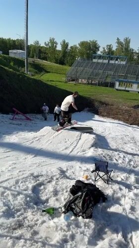Man snowboards artificial slope in sunny Krasnoyarsk summer day