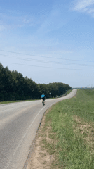 Cyclist rides uphill road through rural Russian countryside