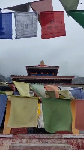 Prayer flags and mountain mist at a Jispa roadside shrine