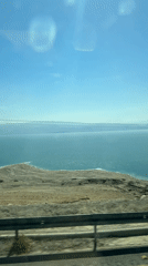 Vehicle travels coastal road near Dead Sea under clear skies
