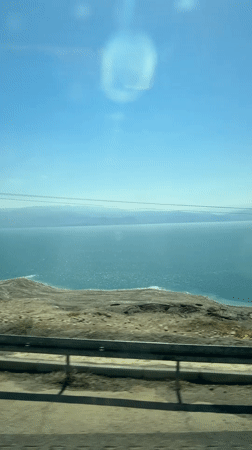 Vehicle travels coastal road near Dead Sea under clear skies