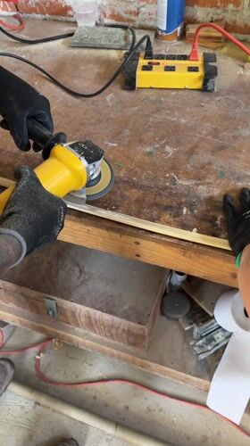 Woodworker sands wooden strip with angle grinder in Mexico