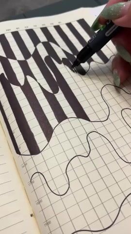 A close-up shot shows a person's hand with green glittery fingernails drawing with a black marker on a grid-lined page in a notebook. The drawing features black stripes that appear to be warping and bending, creating an optical illusion. The marker is actively adding black ink to one of the wavy lines. The notebook page also has time markings along the left edge.