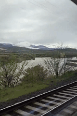 Train passenger films river valley and mountains through clouds