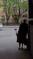 Elderly woman stands in Moscow building alcove