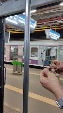 Holding on during a Mumbai commute, station platform rolling past