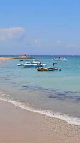 Morning beach activities in Denpasar feature kitesurfing and group gatherings