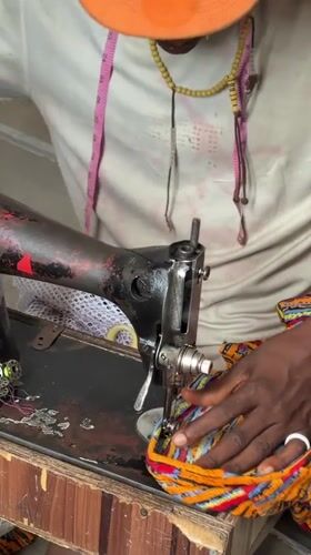 Tailor operates vintage sewing machine on stairs in Nigeria