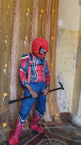 Person in Spider-Man costume with walking stick in Nigerian bedroom