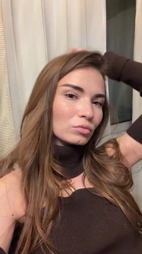 Woman poses indoors in Romashkovo home with modern chandelier