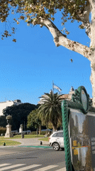 Silver car crosses Buenos Aires intersection near flagpole