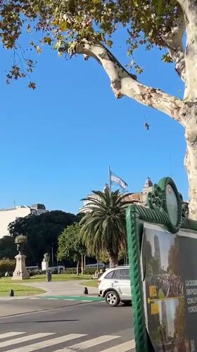 Silver car crosses Buenos Aires intersection near flagpole