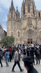 Tourists gather at Gothic cathedral in Barcelona under overcast skies