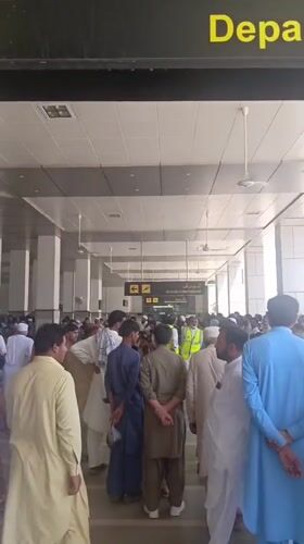 Families in traditional dress navigate Peshawar airport terminal