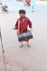 Child counts money on street with drum nearby