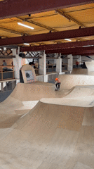Scooter rider performs tricks at indoor skatepark in Corby